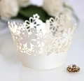 Macro shot of off-white laser-cut floral cupcake wrappers with pearlescent crown detail - Ivory
