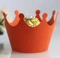 Detailed macro view of an orange crown-shaped paper cupcake liner holding a chocolate - Orange Red
