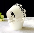 Detailed laser-cut white cupcake wrapper featuring elegant bow patterns and intricate textures - White