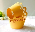 Close-up of golden hollow cupcake wrapper with intricate laser-cut bow patterns - Gold Yellow