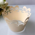 Macro detail of laser-cut pearl paper cupcake wrapper with bow patterns for weddings - Jewelry Cream Star