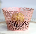 Intricate pink laser-cut floral vine cupcake wrapper on a white decorative plate - Pink