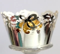 Macro detail of laser-cut silver cupcake wrapper with floral vine patterns - Reflective Silver