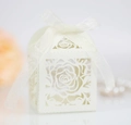 Macro shot of laser-cut rose patterns on a cream wedding candy box with ribbon - Ivory