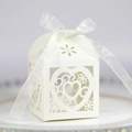 Macro detail of laser-cut heart pattern on pearlescent wedding candy gift box with ribbon - Ivory