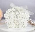 Close-up of laser cut hollow floral wedding candy box with a white organza ribbon bow - Ivory