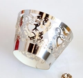 Close-up of laser-cut silver cupcake wrapper with intricate heart and floral patterns - Reflective Silver