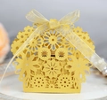 Close-up of laser-cut hollow candy gift box with elegant yellow ribbon bow and floral patterns - Gold