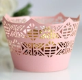Close-up of pink laser-cut cupcake wrappers with geometric patterns and crown edges - Pink