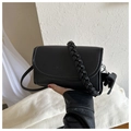 Detail of black crossbody bag with woven handle, embossed logo and bow charm accessory - Black With Pendant