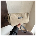 Detalle del bolso cilíndrico de pana beige con correa de cuero negro y etiqueta de la marca - Caqui