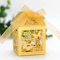 Close-up of golden laser-cut wedding favor box with butterfly pattern and ribbon - Gold