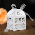 White laser-cut favor boxes with reindeer design and white organza ribbon on wood surface - White