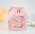 Detailed macro view of laser-cut pink wedding favor box with a satin ribbon and floral patterns - Pink