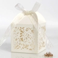 Detail view of laser-cut hollow pattern and ribbon bow on beige wedding favor gift box - Ivory