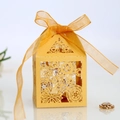 Macro view of laser-cut hollow floral pattern candy gift box with yellow ribbon bow - Gold