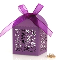 Close-up of purple laser-cut wedding favor box with a satin ribbon and floral hollow design - Dark Purple