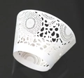 White laser-cut cupcake wrappers with elegant hollowed sunburst patterns on black background - White
