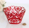 Detail van rode lasergesneden cupcake wrapper met hartvormige patronen en krulversiering - Parelrood