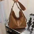 Caramel brown vintage leather tote bag with convertible shoulder straps in a home setting - Brown