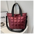 Primer plano de un bolso tote acolchado color burdeos con correas negras y estilo casual - Rojo