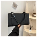 Detalle de bolso de mano rectangular de cuero negro minimalista con logo en dorado - Negro