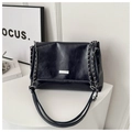 Detailed close-up of dark blue glossy shoulder bag with silver chain and logo plaque - Blue