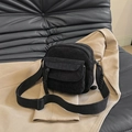 Bolso bandolera pequeño de pana negra con correa ajustable sobre una chaqueta - Negro
