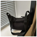 Dettaglio della borsa a mezzaluna in nylon nero minimalista con tracolla larga e zip - Nero