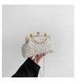 Macro detail of white pleated evening clutch featuring pearl embellishments and gold chain - White