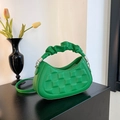 Vibrant green crescent handbag with square texture and pleated handle on black table - Green