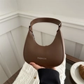 Brown leather crescent underarm bag with Fashion lettering shown in a lifestyle setting - Brown