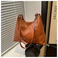 Detalle de bolso de cuero sintético marrón con cadena plateada y grabado de moda - Tostado