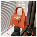 Détail d'un sac à main orange motif crocodile avec boucle en métal doré ondulé gros plan - Orange