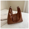 Close-up of brown PU leather tote bag with silver buckles on white textured surface - Brown