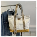 Detail of canvas tote bag showing fashion leather label and colorful jacquard straps - Yellow