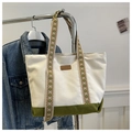 Detail of canvas tote bag showing green ethnic embroidery strap and fashion leather tag - Green