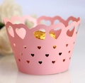 Detailed view of pink laser-cut cupcake wrapper with heart patterns and gold chocolate - Pink