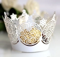 Close-up of laser-cut cupcake wrapper featuring white star and vine patterns - White