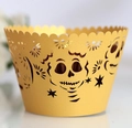 Macro shot of yellow cupcake wrappers with laser-cut skull and floral hollow patterns - Gold
