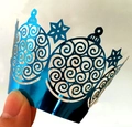 Close-up of laser-cut blue mirror cupcake wrapper featuring snowflake and swirl patterns - Reflective Blue