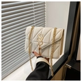 Detail of white quilted handbag featuring golden SS logo, tassel, and chain strap - White