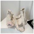 Détail d'un grand sac hobo blanc cassé avec bandoulière large et charm en peluche - Blanc Avec Pendentif