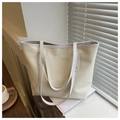 Close-up of cream leather tote bag with gold rivets on a desk with coffee and books - White