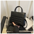 Close-up of black quilted shoulder bag with golden hardware and cylindrical handles - Black