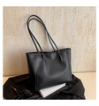 Close-up of a minimalist black leather tote bag on stone texture background - Black