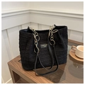 Detail of black textured tote bag with gold chain handles on a cafe table - Black