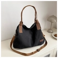 Detail of a black canvas tote bag with brown straps and 'Fashion' label in a home setting - Black