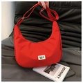 Detalle del bolso de media luna en nylon rojo con etiqueta tejida y estilo deportivo moderno - Rojo
