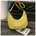 Detalle del bolso de nailon impermeable con correa ajustable sobre fondo de estilo vida - Amarillo